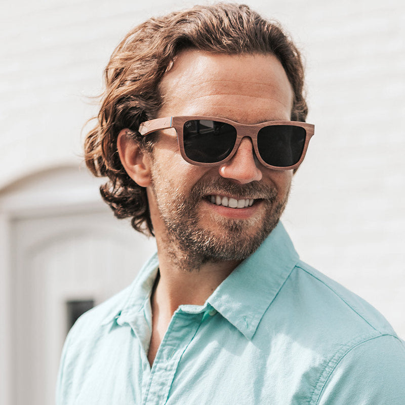 Man smiling wearing eco-friendly wooden sunglasses with grey lenses