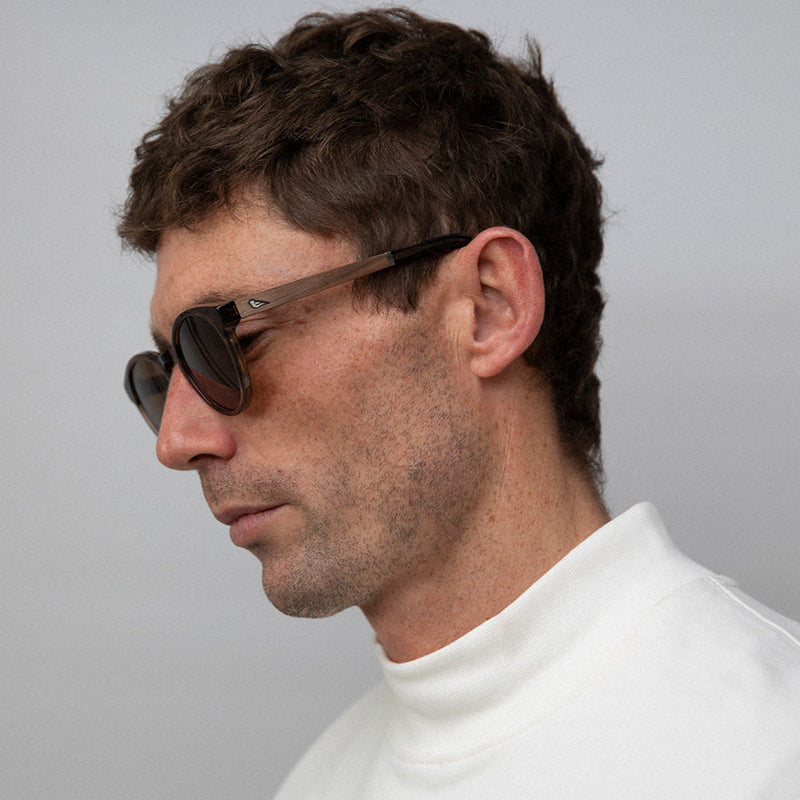 man facing sideways wearing transparent brown acetate sunglasses with amber lenses