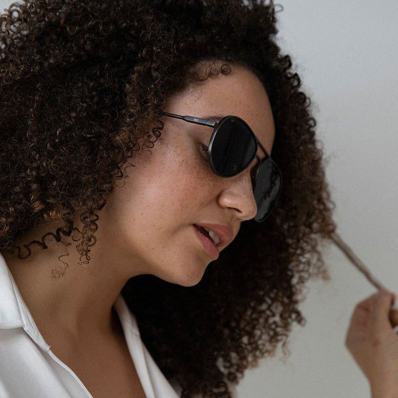 Black woman wearing aviator sunglasses with polarised lenses looking down