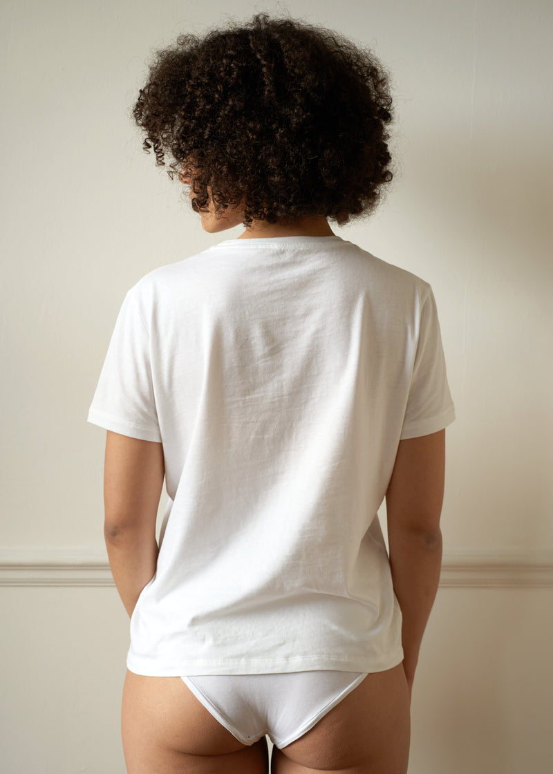 Single Pocket White T shirt. Relaxed fitting. On female model size small with dark afro hair. Worn with the white briefs back view