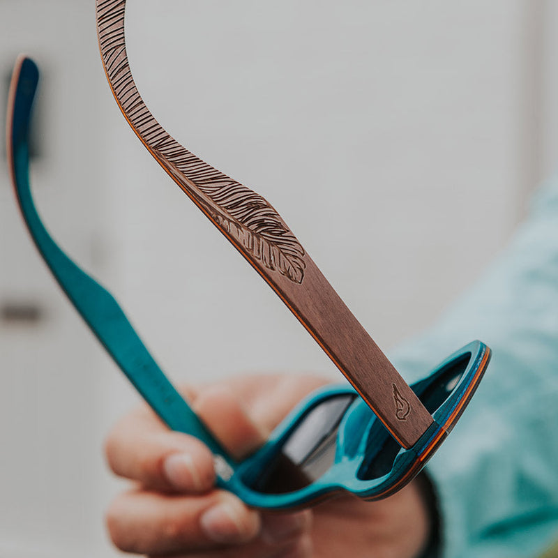 Hands holding a pair of eco-friendly wooden sunglasses with blue wood inside